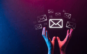 Hands raised against a dark, textured background with a neon glow, as if magically levitating email envelope icons that symbolize digital communication and the concept of building an email list.